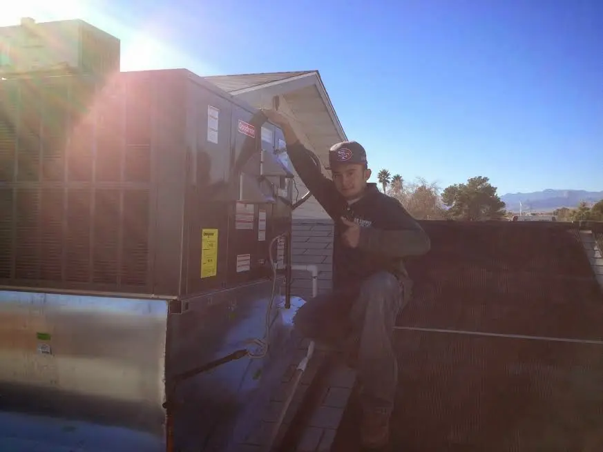 HVAC technician performing Air Duct Repair on a rooftop unit in Champlain